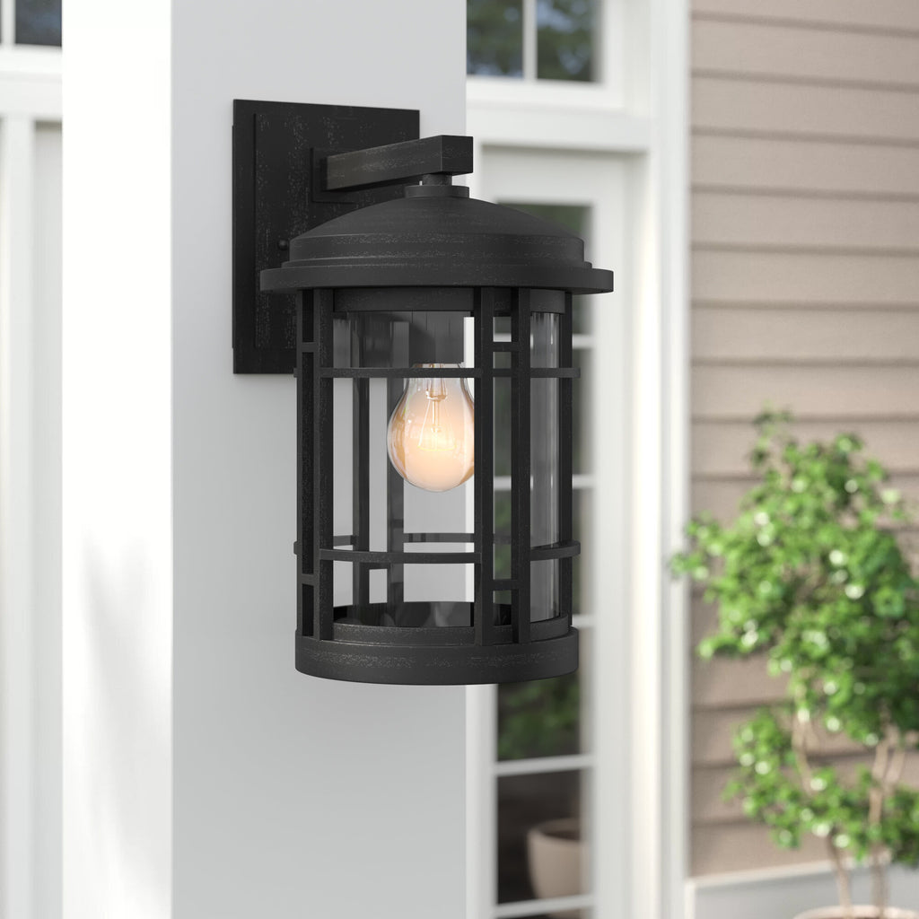 Black outdoor wall light fixture on a house exterior with a blurred background