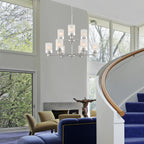 Modern living room with a chandelier, blue sofa, and large windows.