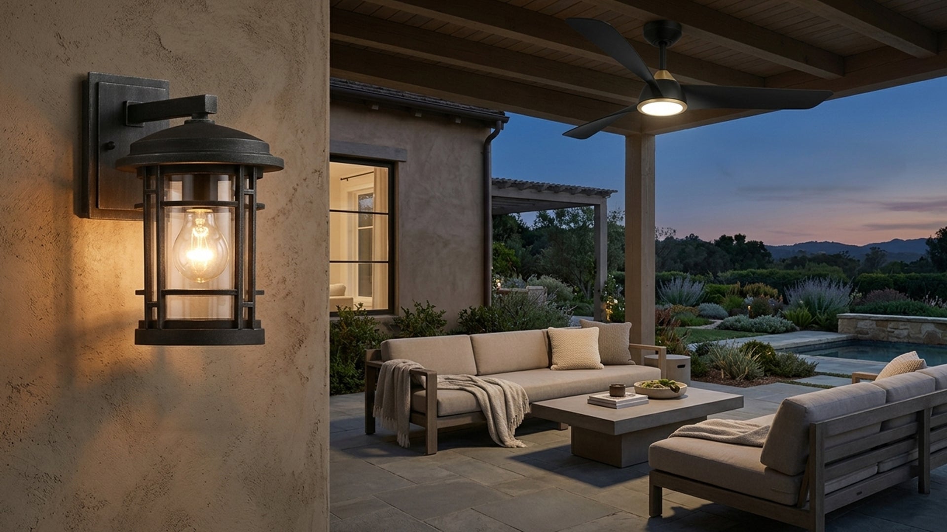 Outdoor patio with beige sofa, coffee table, and wall-mounted lantern at dusk.