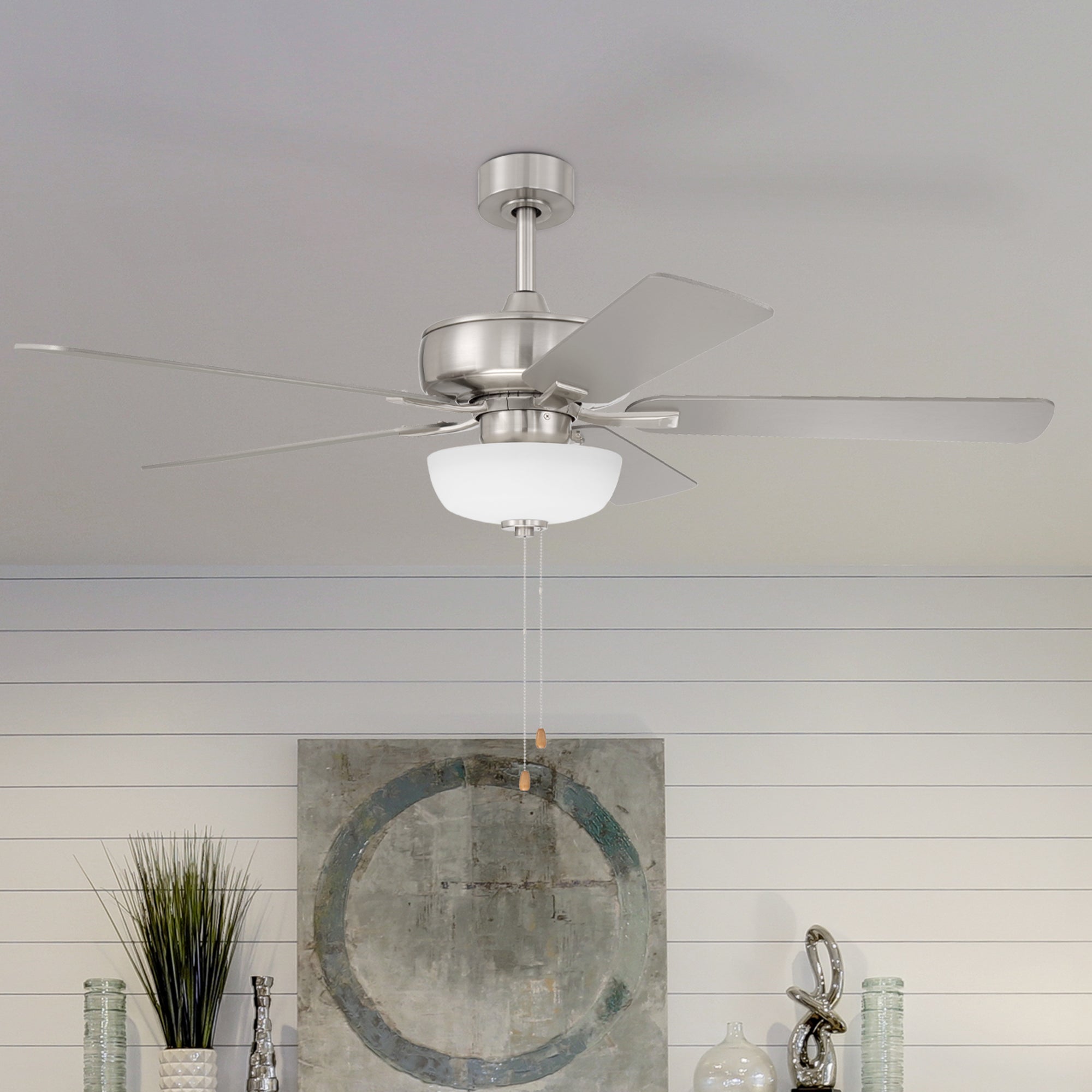 Ceiling fan with light fixture in a room with decorative elements.