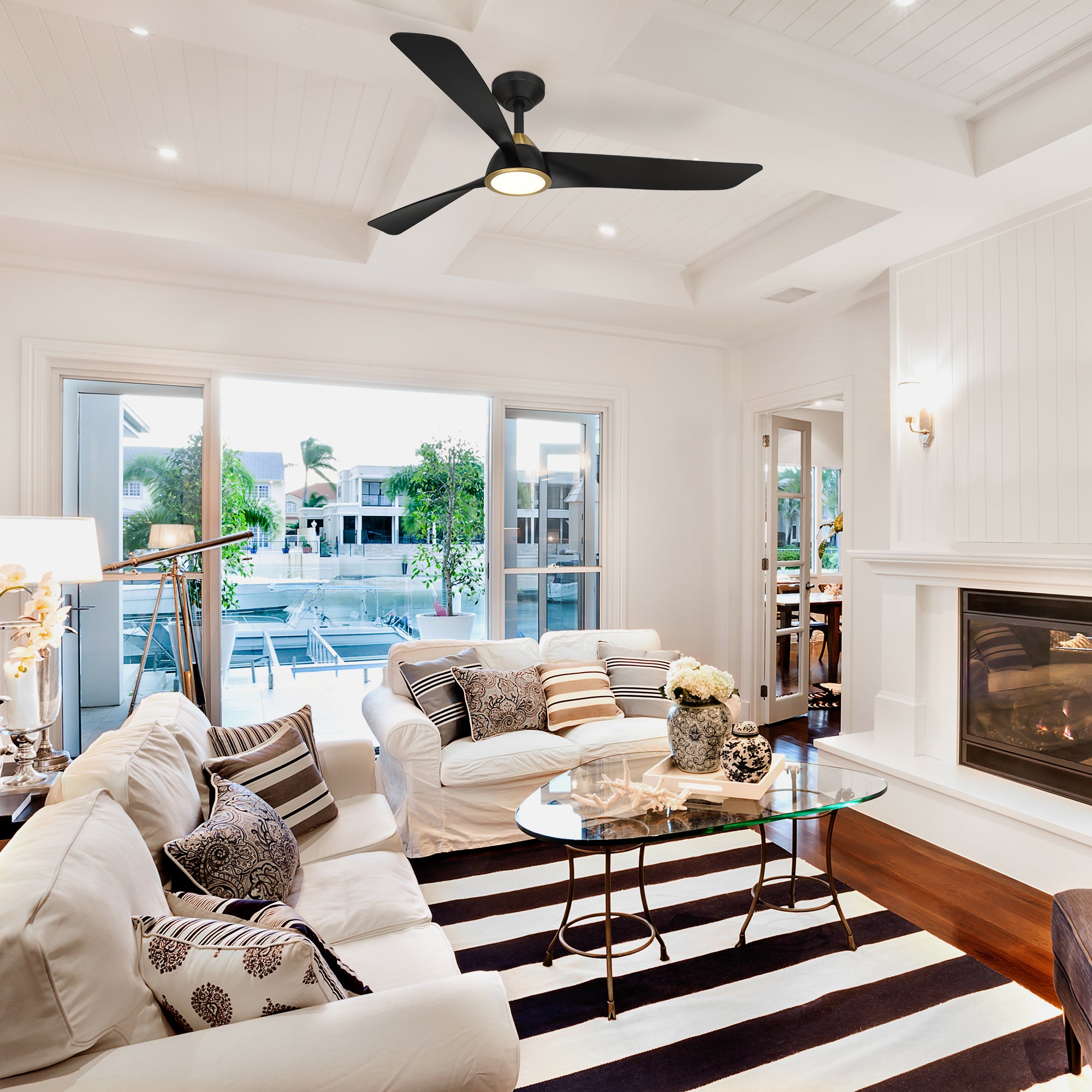 Modern living room with white walls, striped rug, and ceiling fan.