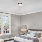 Modern bedroom with gray bed, white walls, and large window.